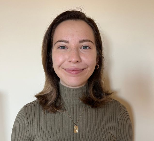 Janet Bromley smiles in front of a tan background.