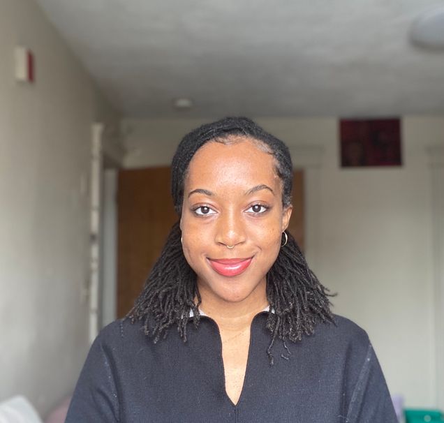 Shelby Barthelmy smiles for a portrait with an office in the backgound.
