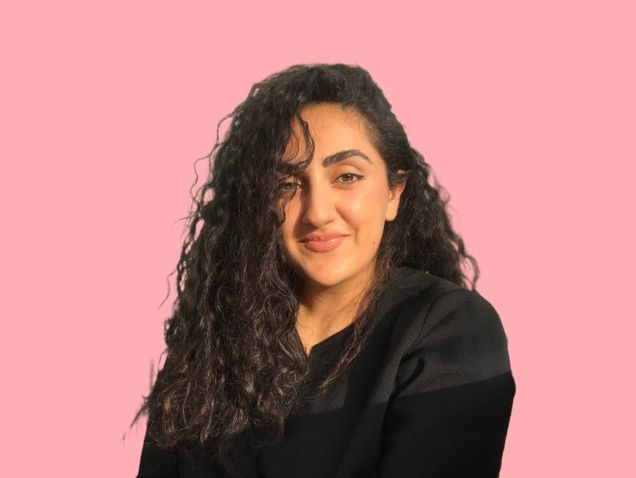 Headshot photograph of Tina Barouti, PhD. Dr Barouti wears all black in front of a solid pink background.