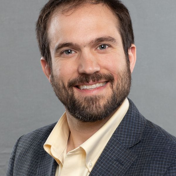 headshot portrait of C. Ian Stevenson, smiling. He is wearing a suit jacket and collared dress shirt.