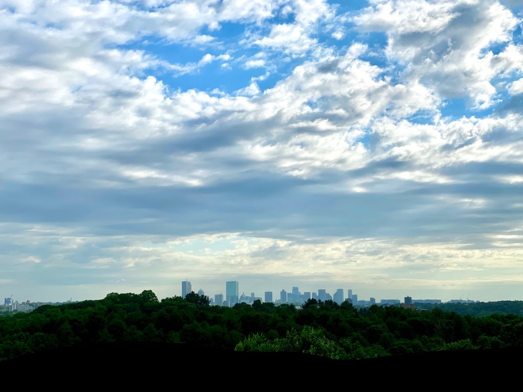 skyline of Boston, Massachusetts with a cloud-filled but bright blue sky.