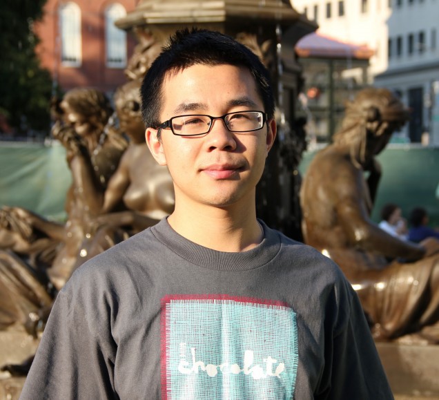 Dan Li stands in front of a statue.