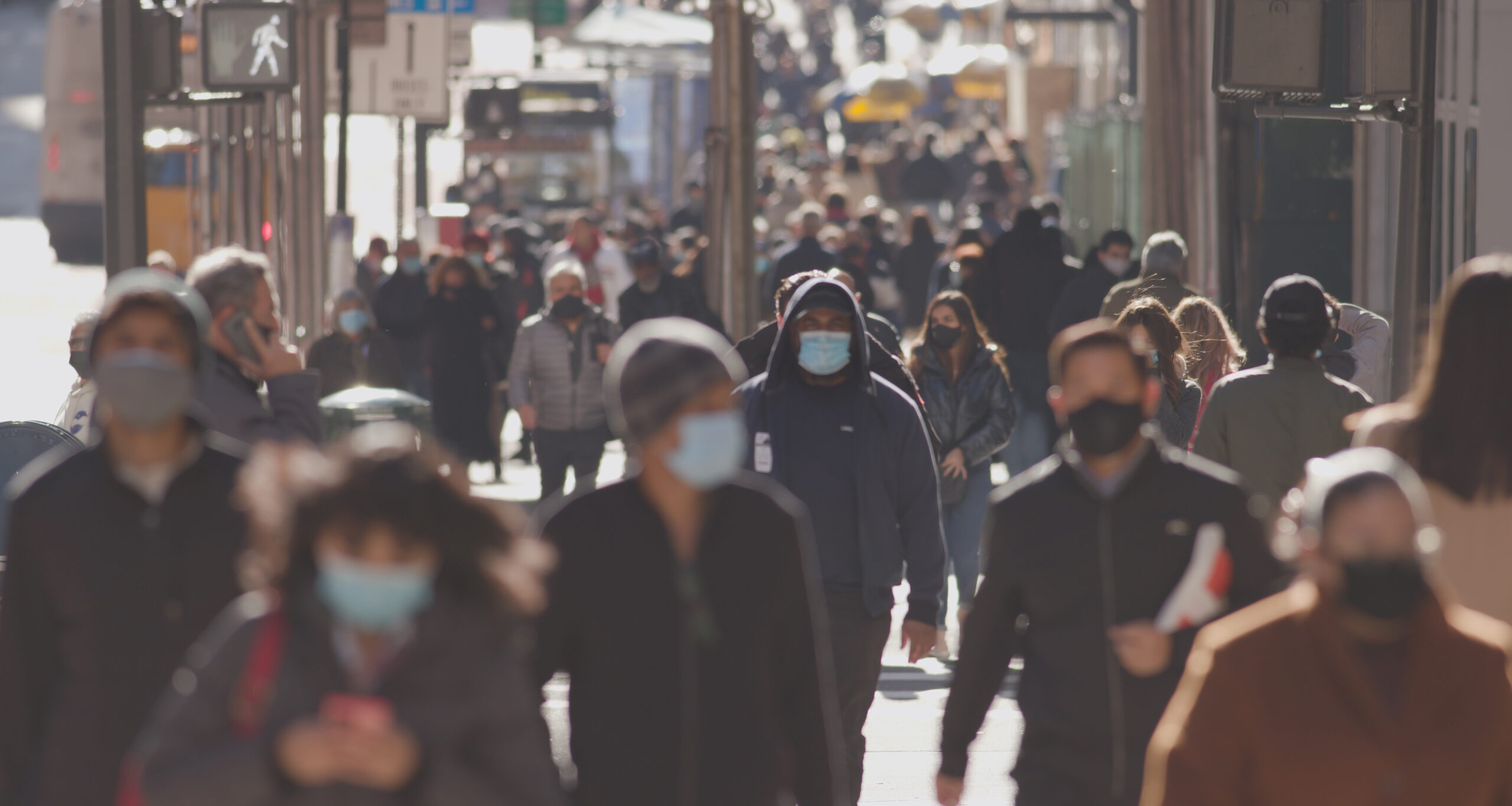 People walking down a street in the city with masks on. Pandemic. 