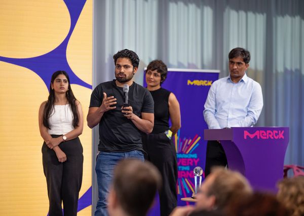 students presenting at a competition, standing on a stage, one with microphone in hand