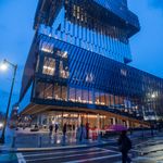 Photo: The CDS building on BU's campus, a tall glass structure, at night during the rain