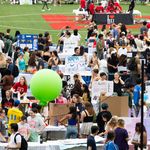 Photo: A large group of college students gathered on a football field on a sunny day for an event about student activities and clubs