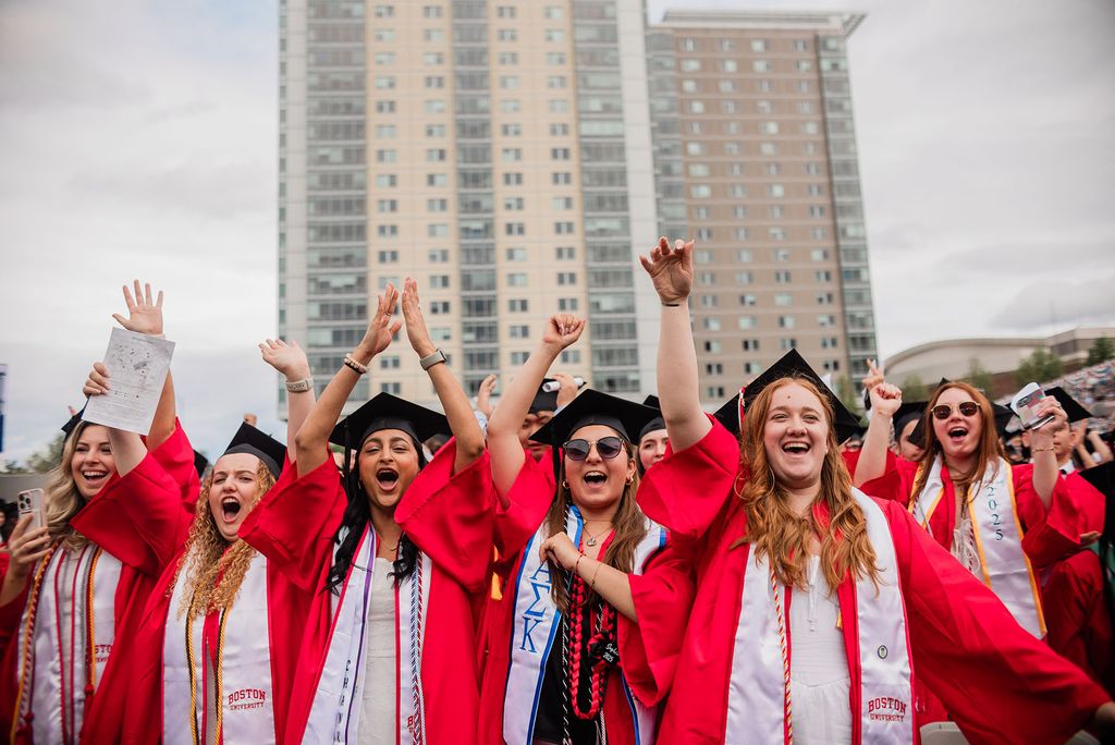 Photo: Students in red graduation gowns cheering during BU's Commencement ceremony