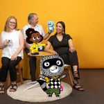 Photo: Three people smiling and posing with animations of characters from "Lyla in the Loop" and "Carl the Collector" added into the image