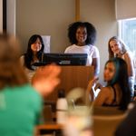 Photo: A shot of young students presenting their research behind a podium.