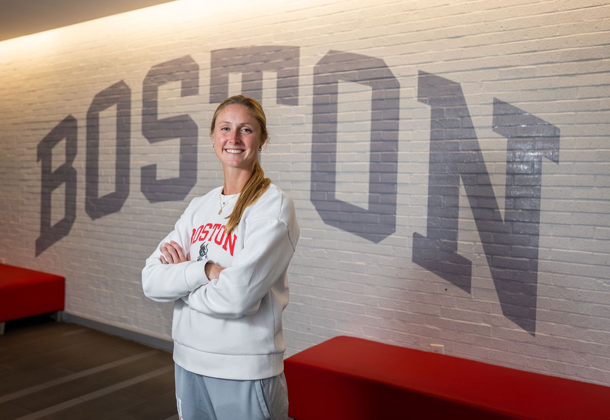 Photo: A white woman with blonde hair poses with her arms crossed in front of a brick wall with BOSTON painted in gray.