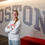 Photo: A white woman with blonde hair poses with her arms crossed in front of a brick wall with BOSTON painted in gray.