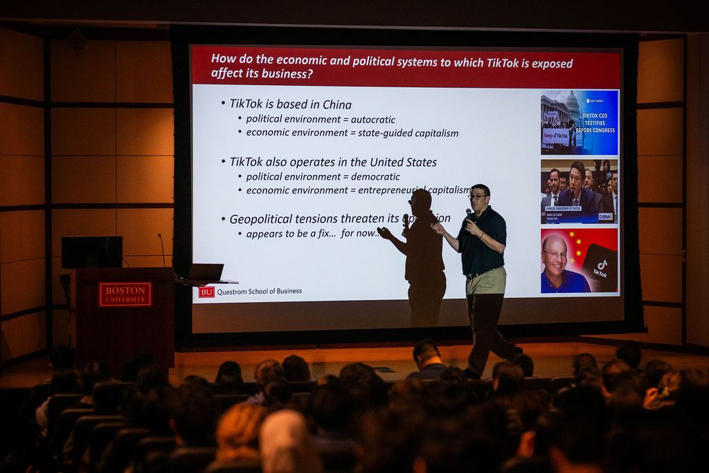 Photo: Jeffrey Furman, a Questrom School of Business professor at Boston University, standing in front of a screen that has the text "How do the economic and political systems to which TikTok is exposed affect its business?" during a class