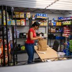 Photo: A lone individual in a red shirt stocks and organizes the BU food pantry.