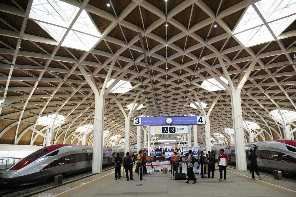 Photo: A red and silver high-speed train is parked during the opening ceremony for launching Southeast Asia's first high-speed railway at Halim station in Jakarta, Indonesia on Oct. 2, 2023. People stand under a large banner set up on the middle platform of the open-air train station.