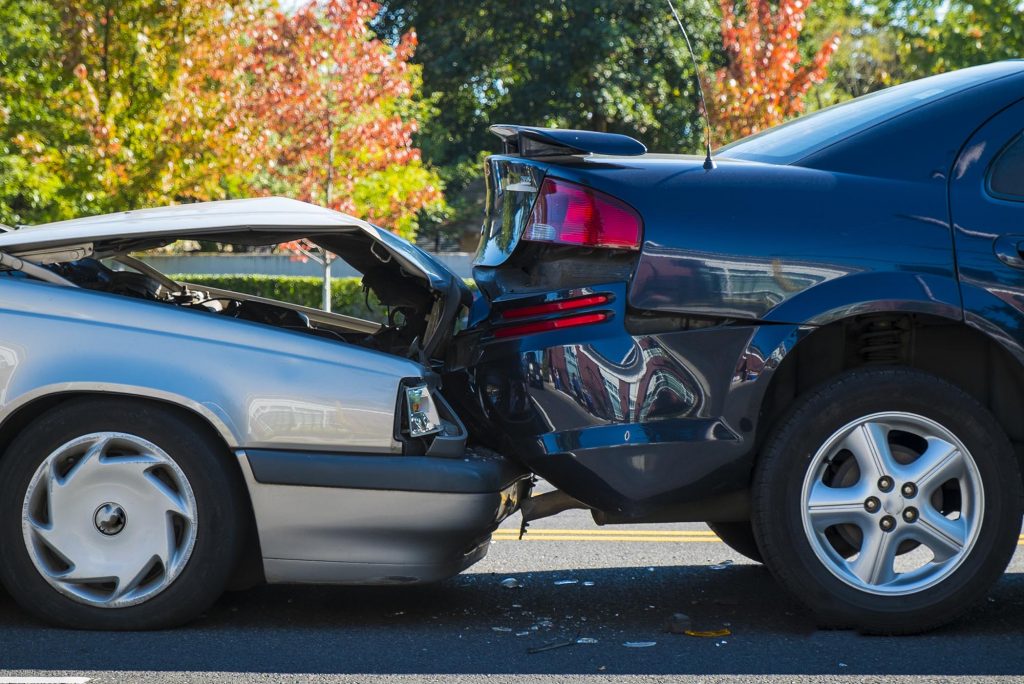 Photo: Close-up of a car accident involving two cars on a city street. The cards were in a "fender bender" and shows one car crashed into the rear end of another.