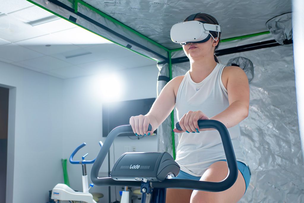 Photo: A woman on a cardio machine wearing a VR headset.