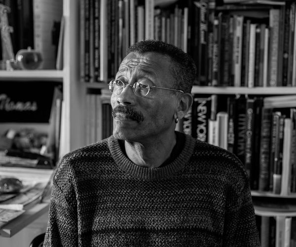 Photo: A black and white photo of production designer Wynn Thomas in front of a bookshelf