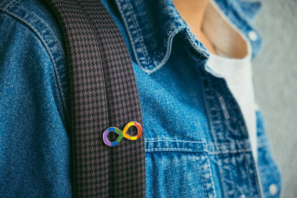 Photo: A boy wearing a jean jacket and an autism infinity rainbow symbol pin on his backpack strap