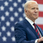 Photo: President Joe Biden delivers remarks during a campaign event with Vice President Kamala Harris in Raleigh, N.C. He stands in front of an American flag with a navy suit and red tie.