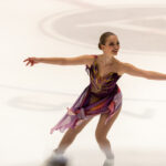 Photo: Clara Neal skates with her arms open and wide as she smiles during her performance.