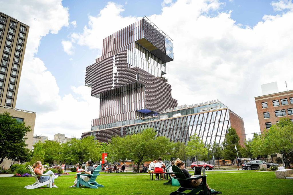 Photo: Boston University's COM Lawn filled with students on a sunny day. The Center for Computing and Data Sciences on Boston University's campus is visible in the background