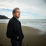 “I had the good luck to be raised among expert joke-tellers, complainers, arguers, schmoozers, boasters, and liars,” Pinsky says in his new memoir, Jersey Breaks. Photo by Gabriela Hasbun. Pinsky stands looking out over an ocean beach on a cloudy day