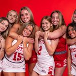 Photo: Four sets of sisters on the BU field hockey team smiling and hugging in uniform in front of a red background