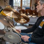 Photo: A man sitting behind a drum kit and playing