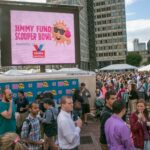 Photo: A picture of an outdoor ice cream event. A large screen says "Jimmy Fund Scooper Bowl"