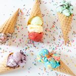 Photo: Stock image of five different ice cream waffle cones artistically laid about with various rainbow sprinkles in between.