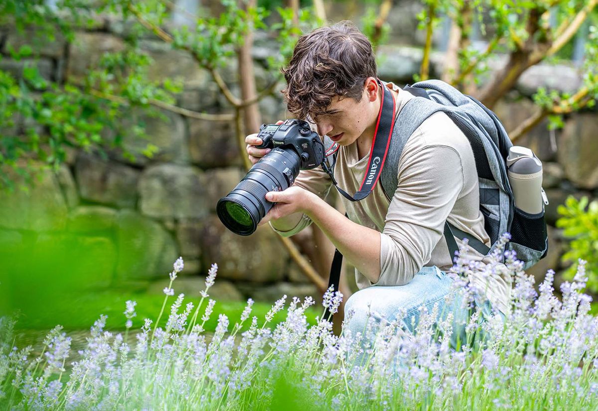 Photo: A person taking a photo, with a professional camera, of flowers in a field