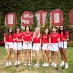 Photo: A group shot of the BU women's golf team in there uniforms with a wall in the background that reads BOSTON.