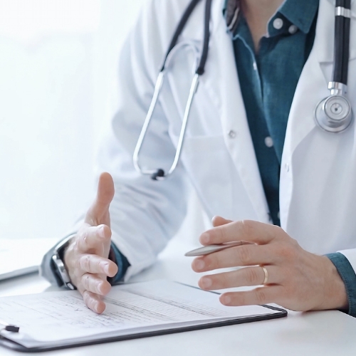 A physician in a white coat with a stethoscope and clip board