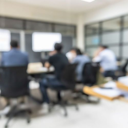 Blurred images of a group of people at a table in a conference room