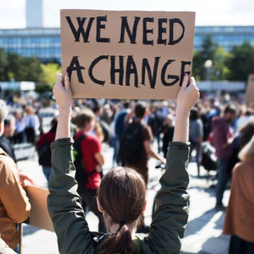Protestors hold a sign that reads: We need a change