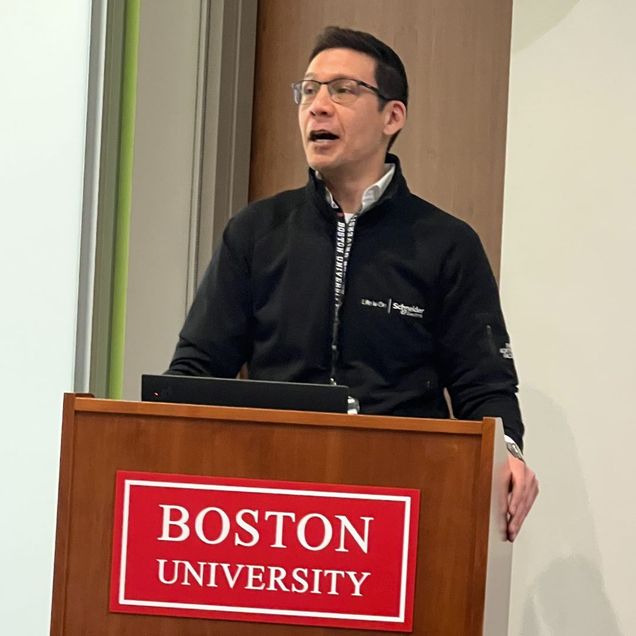 A person lectures from behind a Boston University lectern