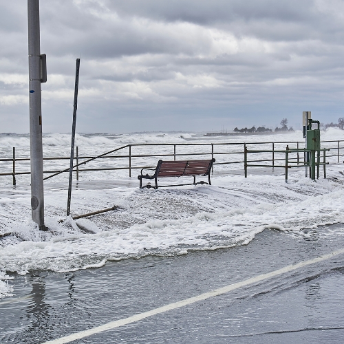 Flood on a paved street with a bench.