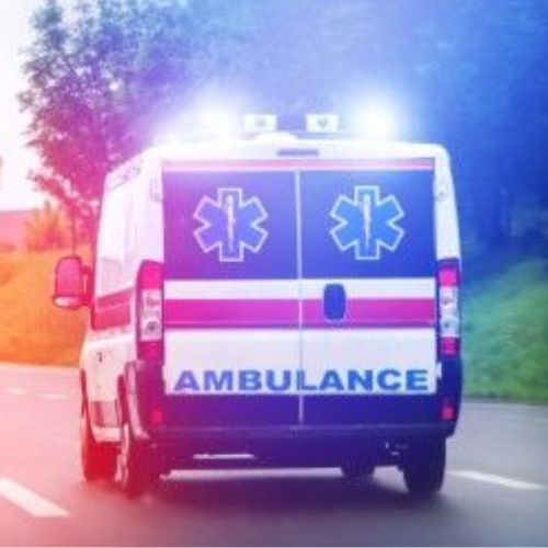 An ambulance with its lights on driving down a street.