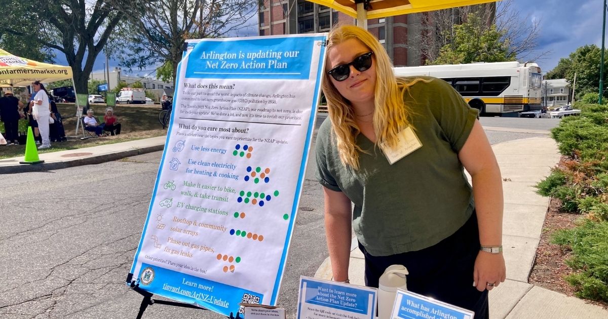 A student in an outdoor tent with an interactive poster board about Net Zero action.