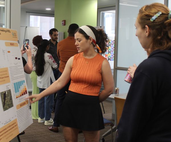 A student showcases a research poster to other students.