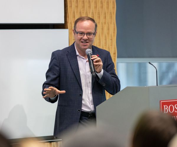 Benjamin Sovacool holds a mic at a BU podium.