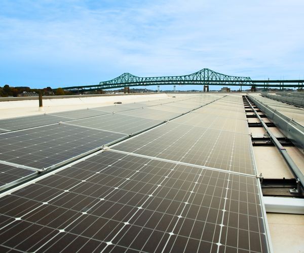 Solar panel in foreground with bridge in background.