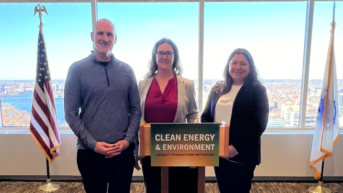 Three people pose in front of a podium.