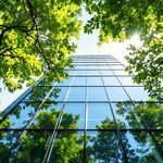 Glass skyscraper building with trees in front.