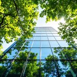 Glass skyscraper building with trees in front.