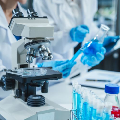 A scientist operates a microscope with test tubes.