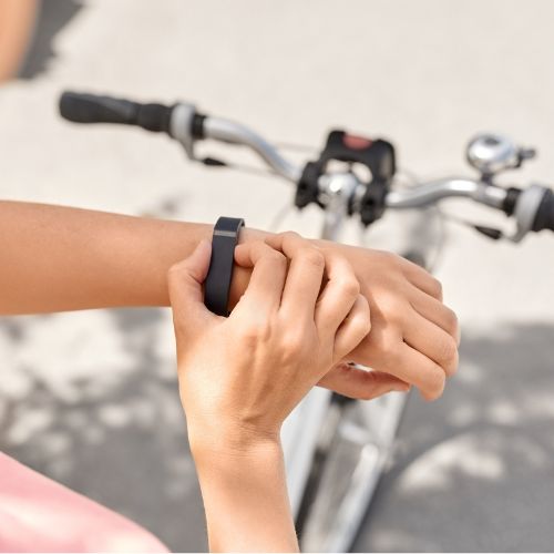 Person uses a wearable device on their wrist while biking.