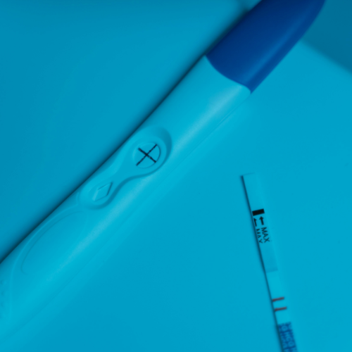 Positive pregnancy test on blue surface.