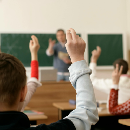 Students raising their hands in a classroom.