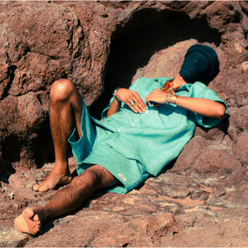 A person laying down on a rock in the sun.